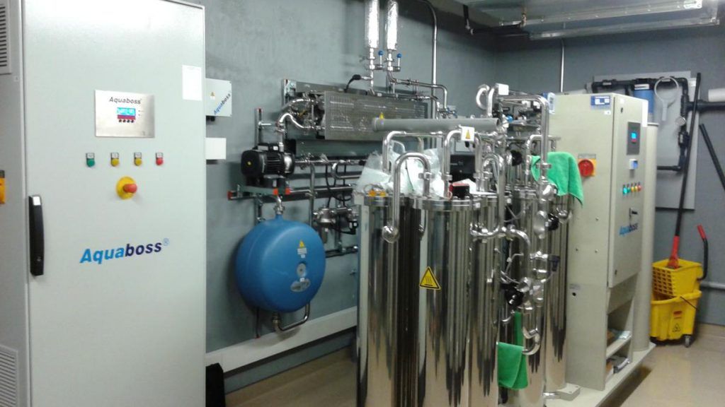 A room with a lot of stainless steel tanks and a yellow mop.