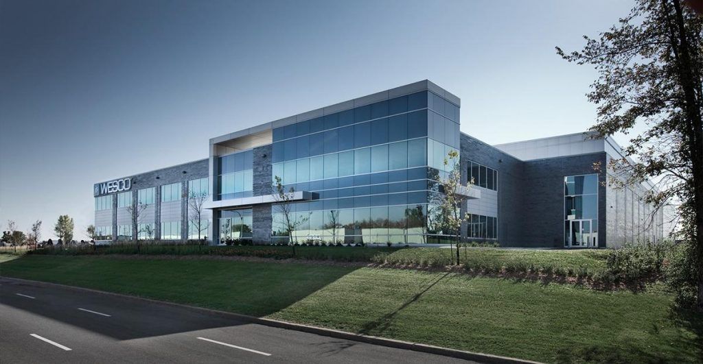 A large building with a lot of windows is sitting next to a road.
