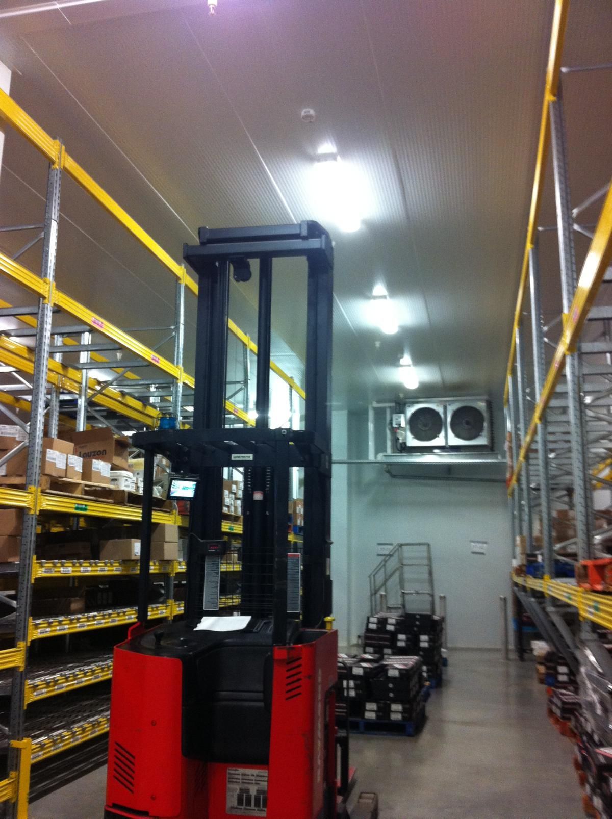 A red forklift is in a large warehouse