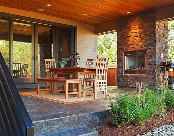 A patio with a table and chairs and a fireplace