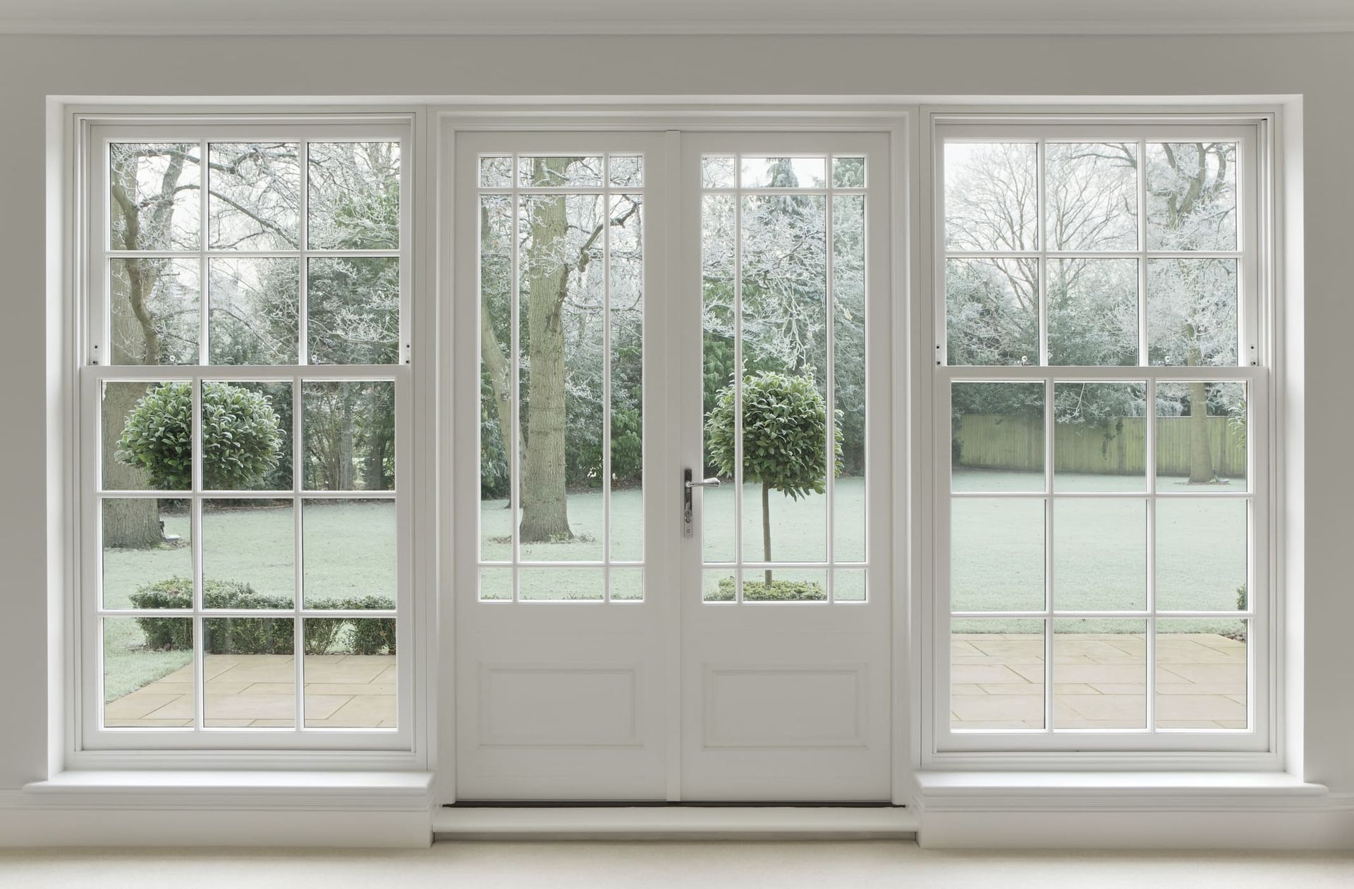White French doors and windows framing a snowy backyard view