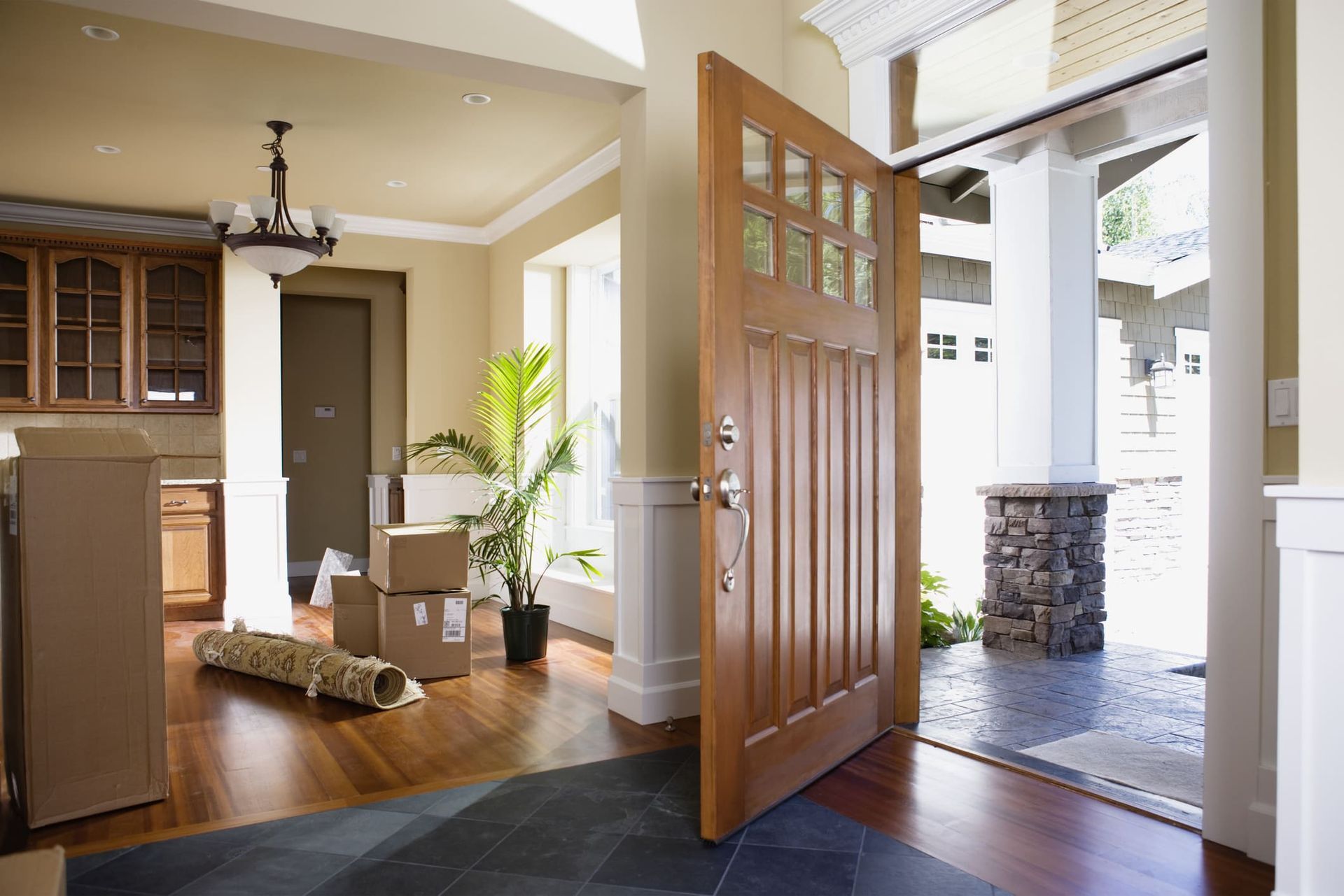 A living room with a door open and boxes on the floor