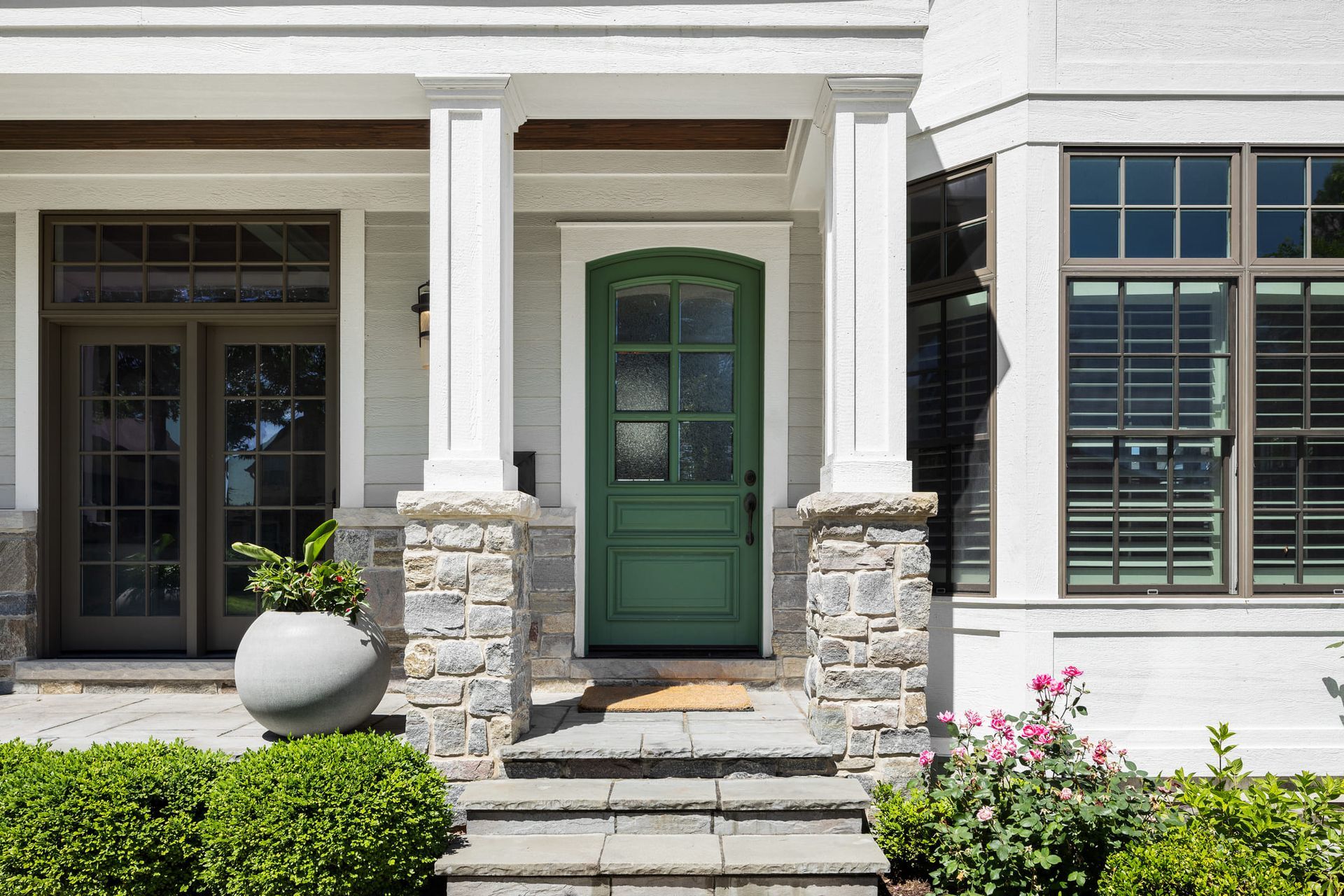 A white house with a green door and stone pillars