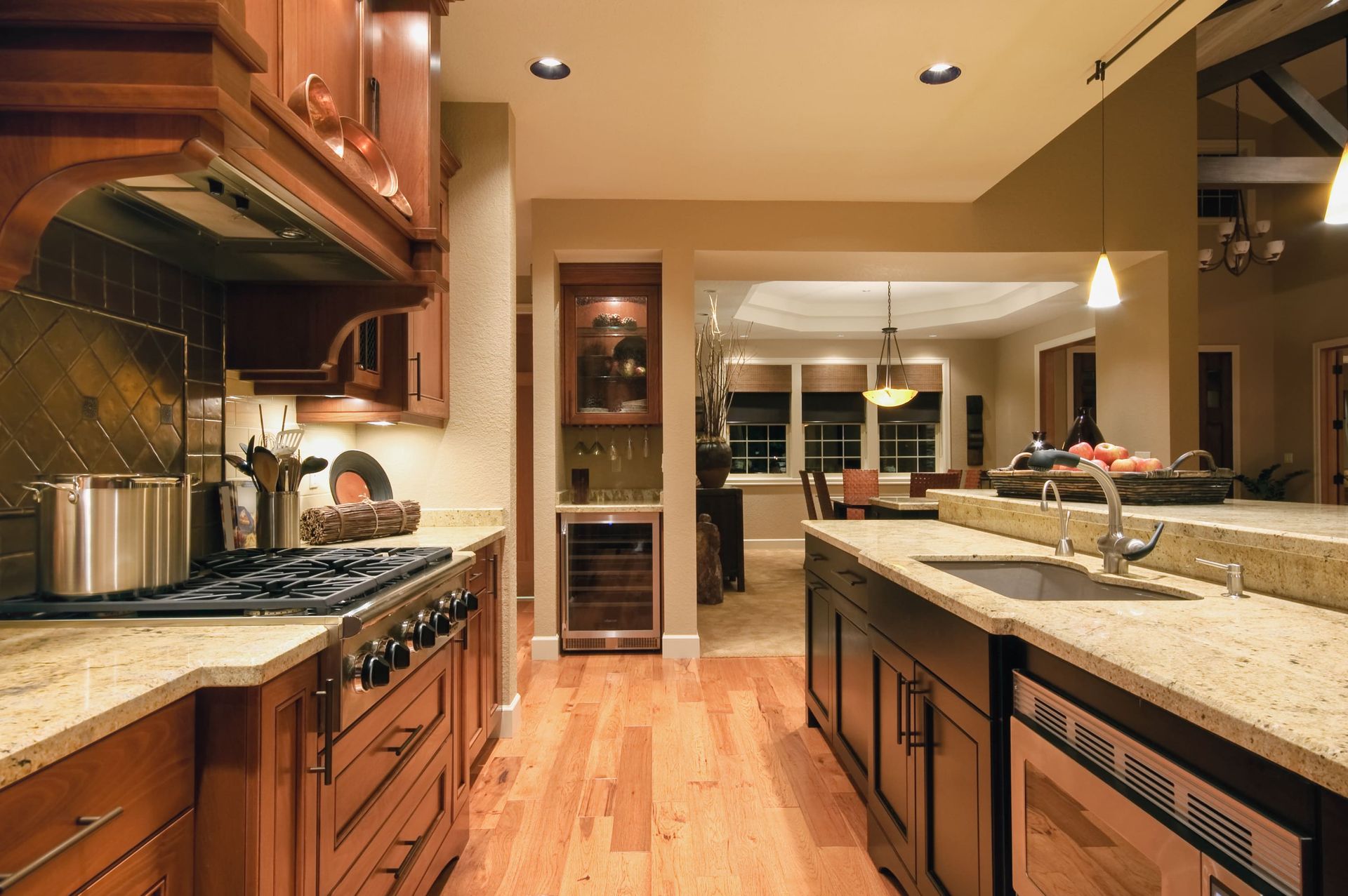 Warm-toned modern kitchen with granite counters, wood cabinets, and stainless steel appliances.