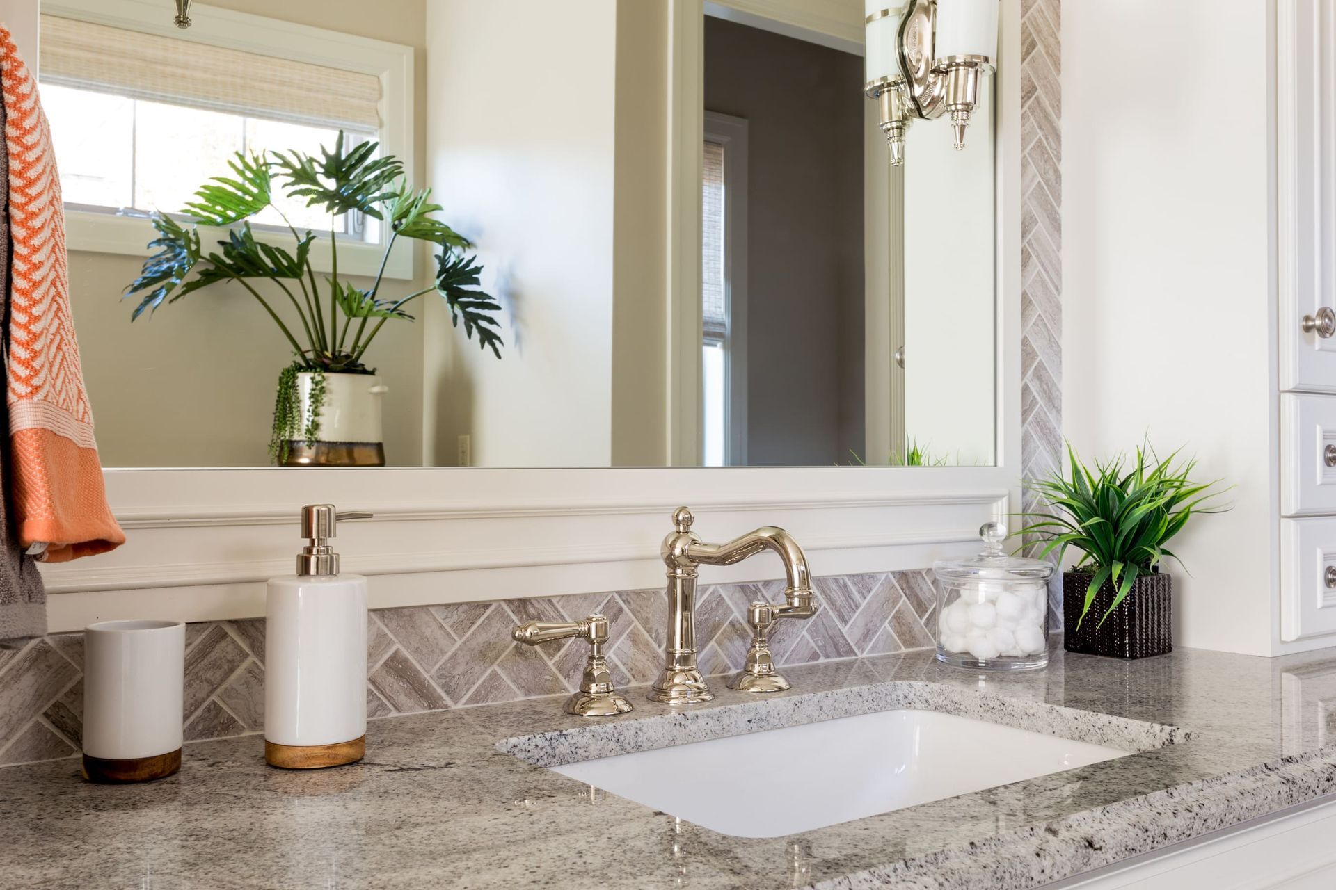 A bathroom with a sink , mirror and soap dispenser.