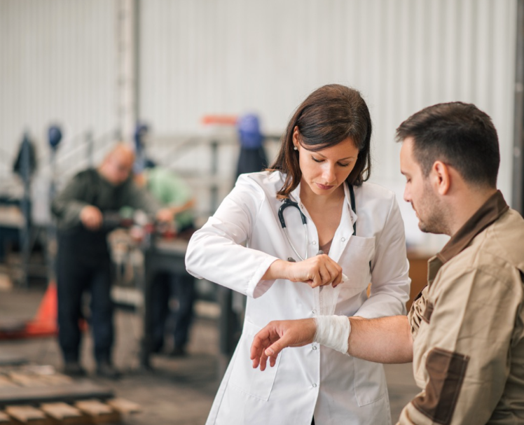A doctor wraps a bandage around a person's write in a warehouse setting.