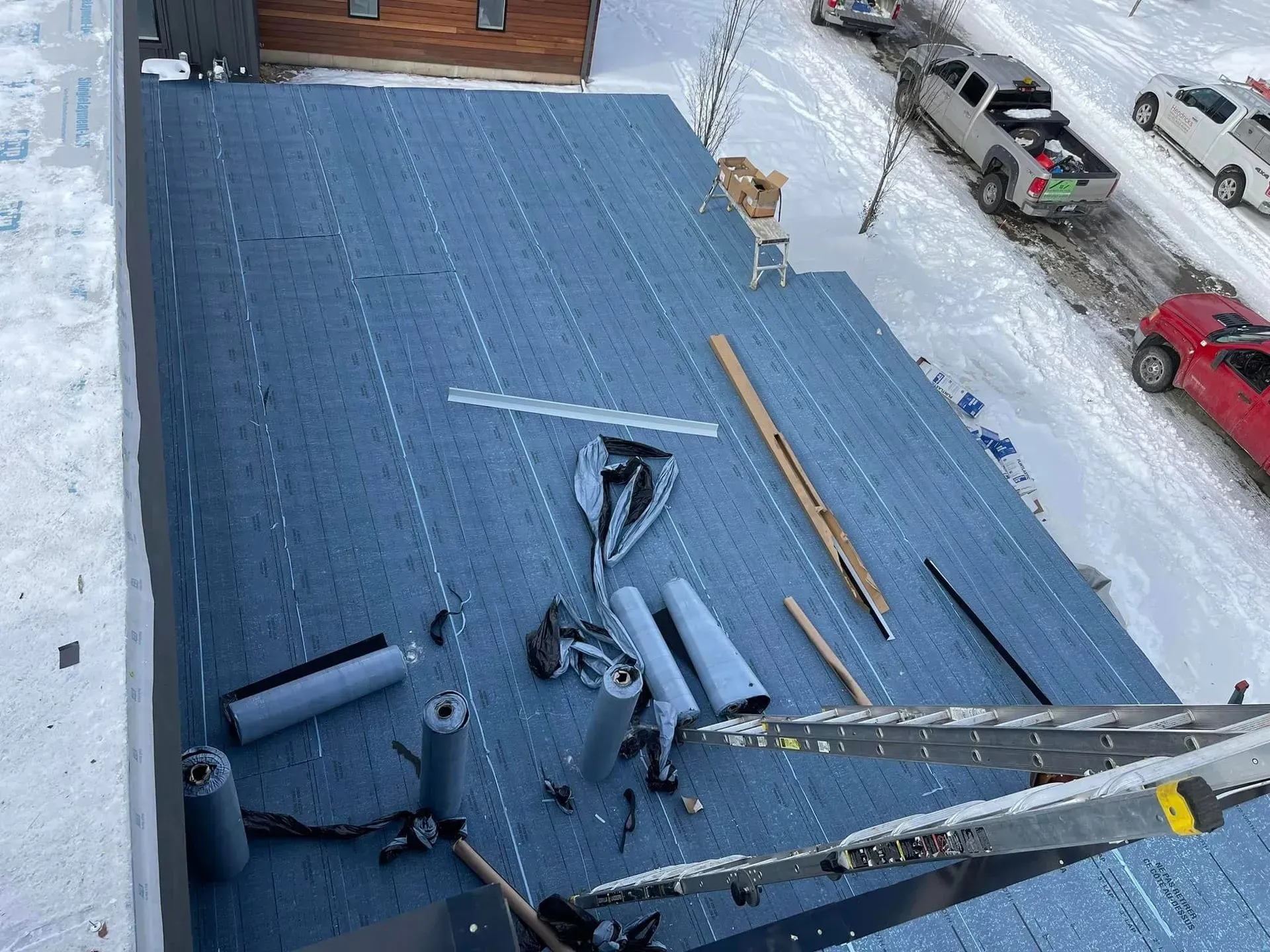 Blue rooftop covered with scattered tools and debris after a likely repair or storm damage