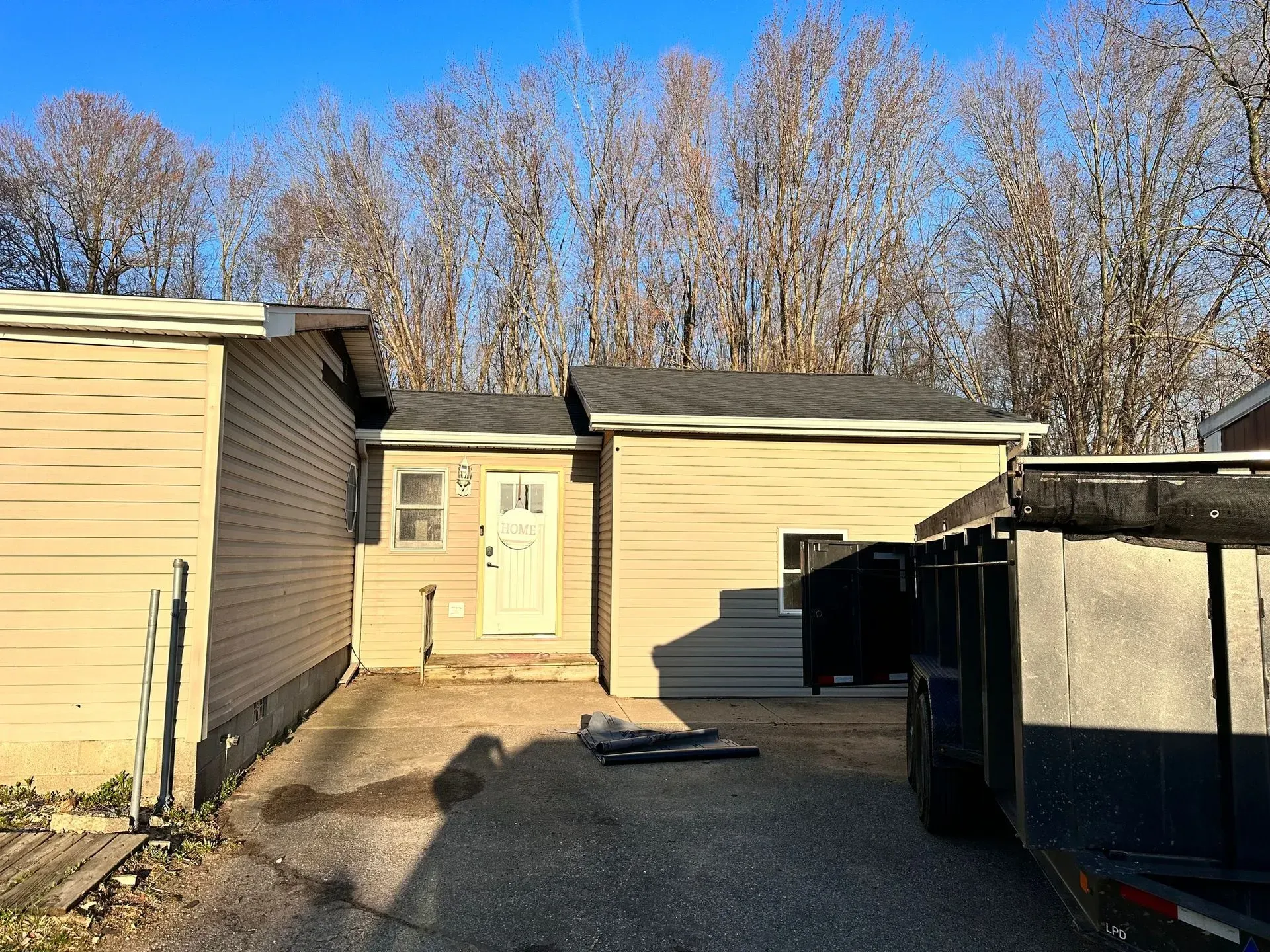 Backyard view of beige buildings, a central white door, and a black dumpster under a clear blue sky.