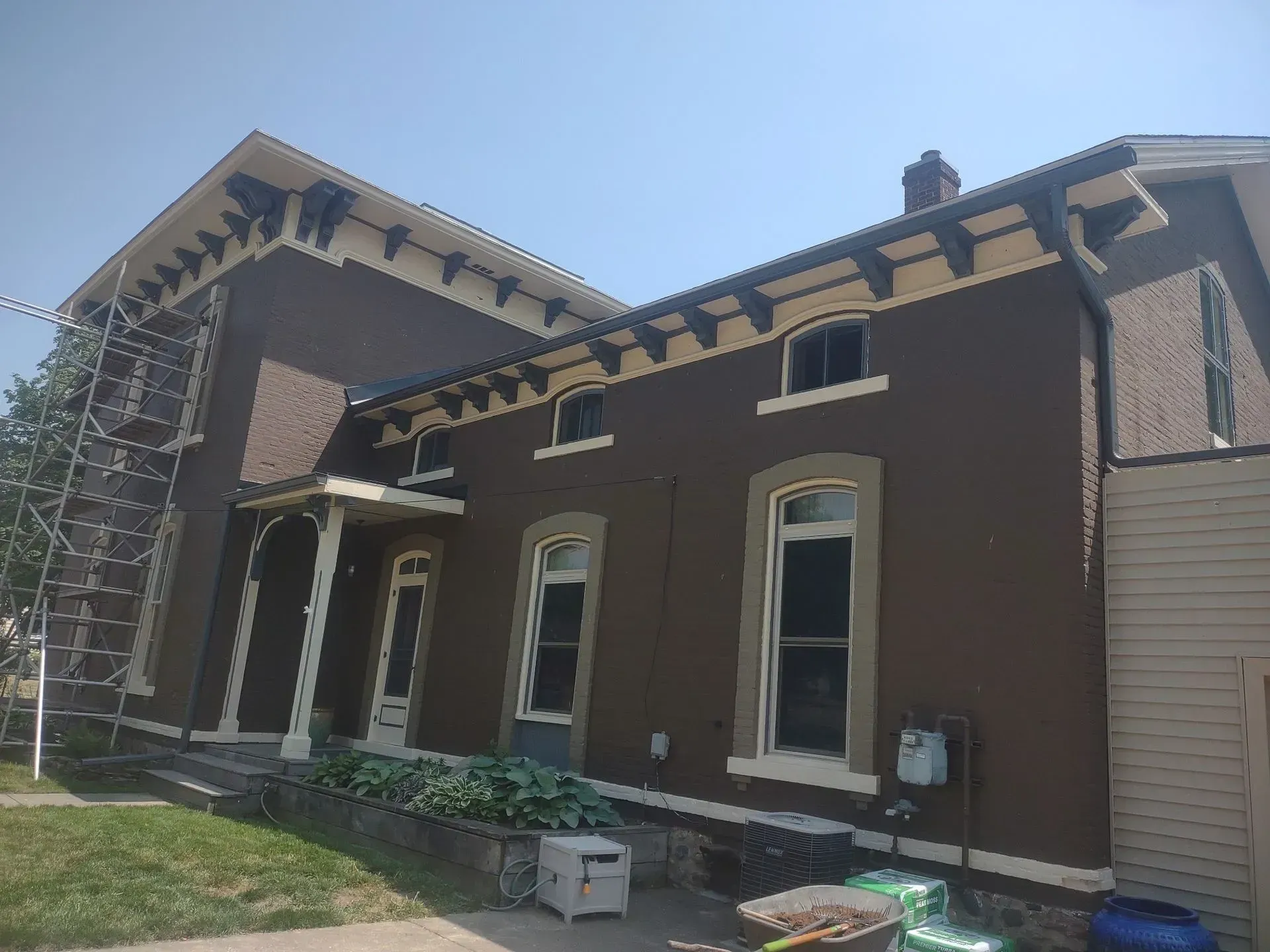 Brown brick building with white-trimmed windows and sloped roof in daylight
