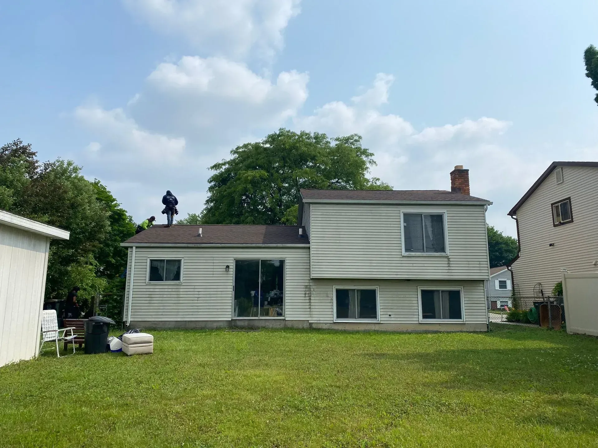 Small white house with green windows and a grassy yard under a partly cloudy sky