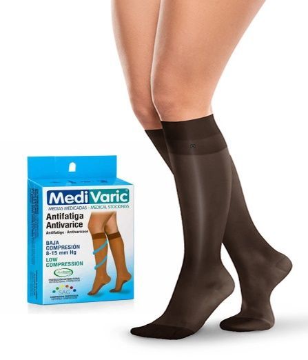 Calcetines de compresión marrones en las piernas, junto a una caja azul de un producto MediVaric.