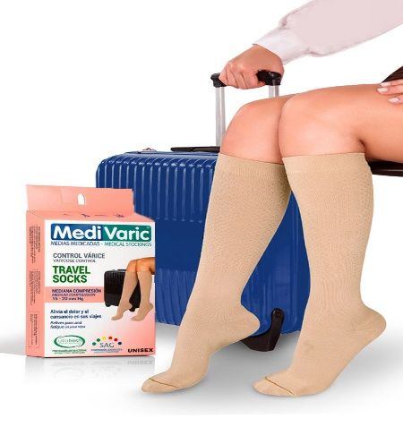 Persona con medias de compresión de viaje color beige junto a una maleta azul y una caja de calcetines MediVaric.