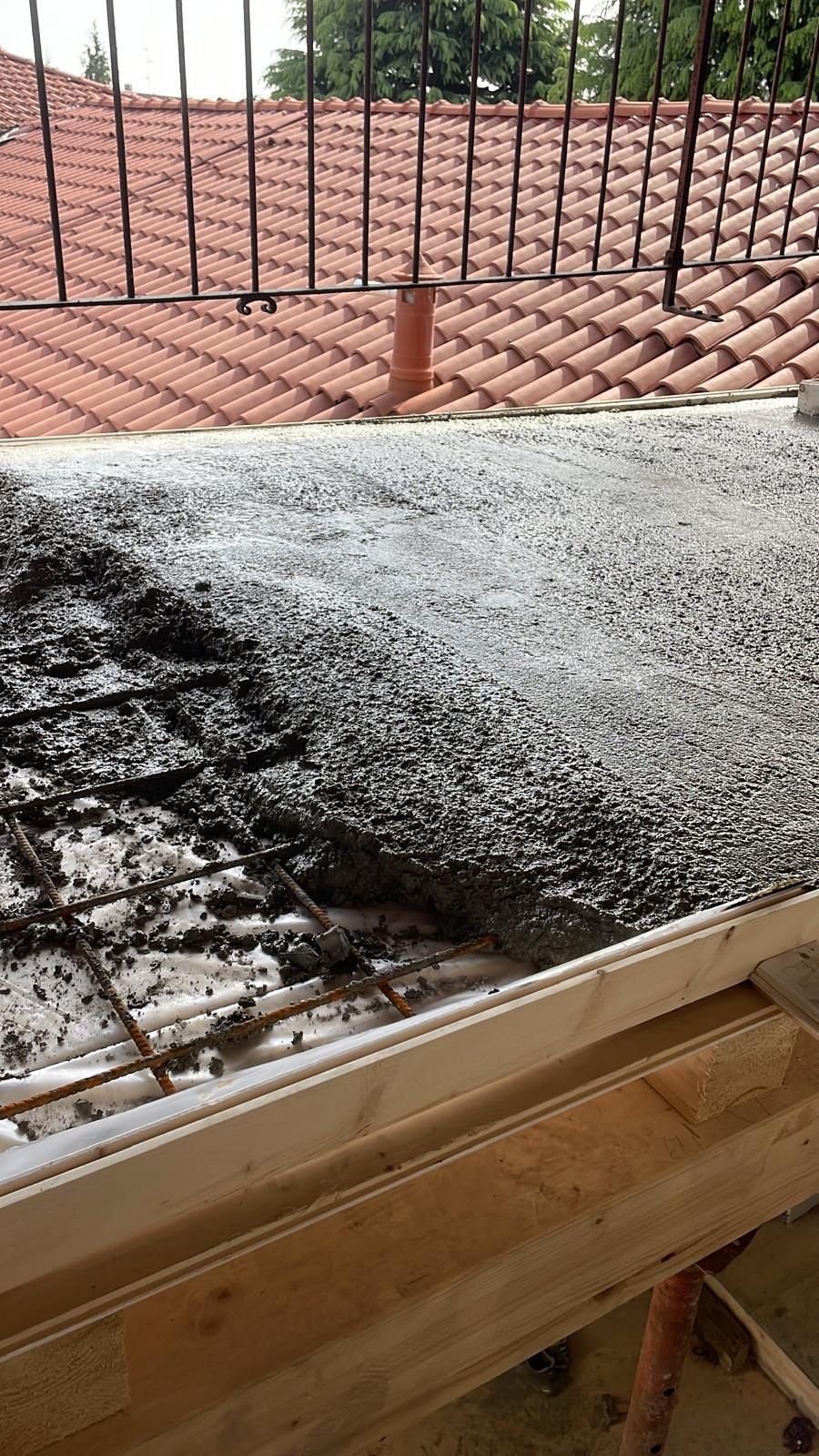 Calce fresca livellata su una cassaforma di legno, con una recinzione metallica sullo sfondo.