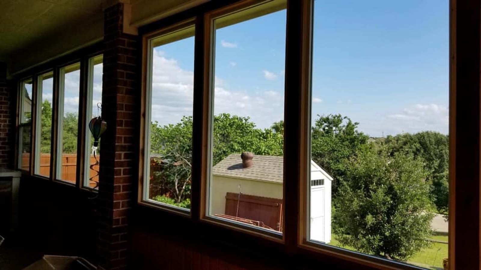 View through several windows of a bright blue sky, trees, and a small white shed.