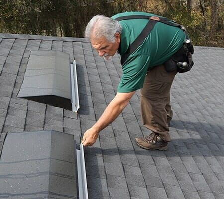 A man in a green shirt is working on a roof