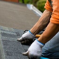 A man is installing shingles on a roof.