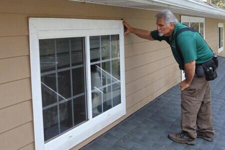 A man is pointing at a window on the side of a house.