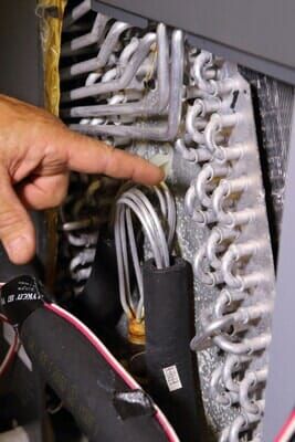 A person is pointing at a coil on a machine.