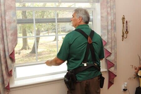 A man in a green shirt is looking out of a window.