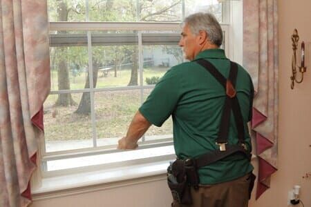 A man in a green shirt is looking out of a window.