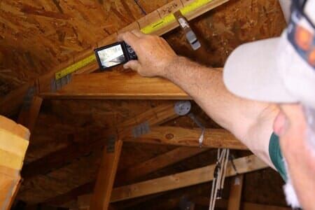 A man is measuring a wooden structure with a tape measure.