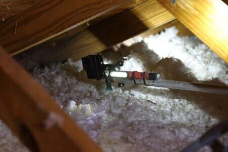 A hose is hanging from the ceiling of an attic.