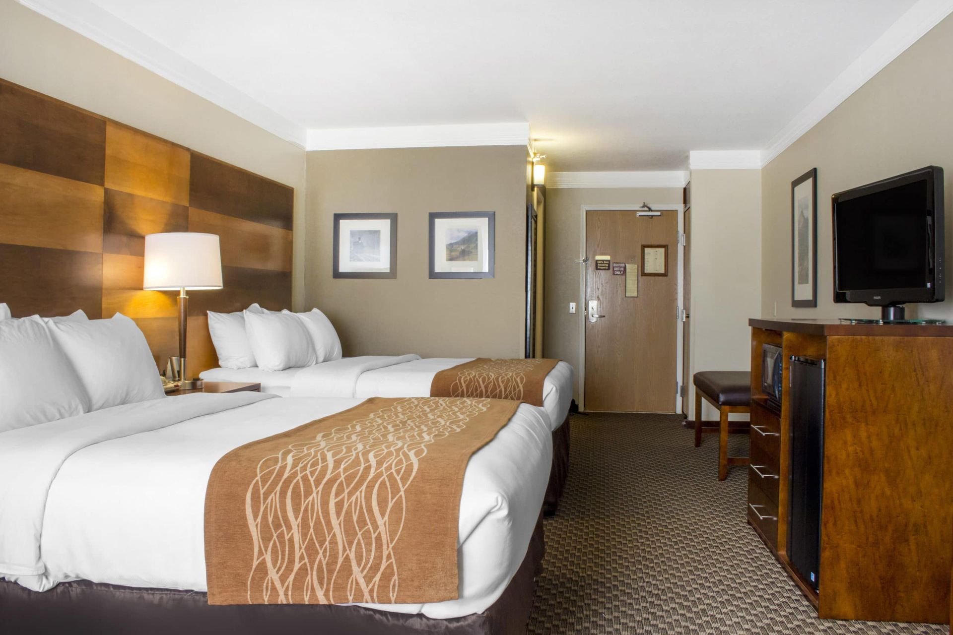 A hotel room with two beds and a flat screen tv.