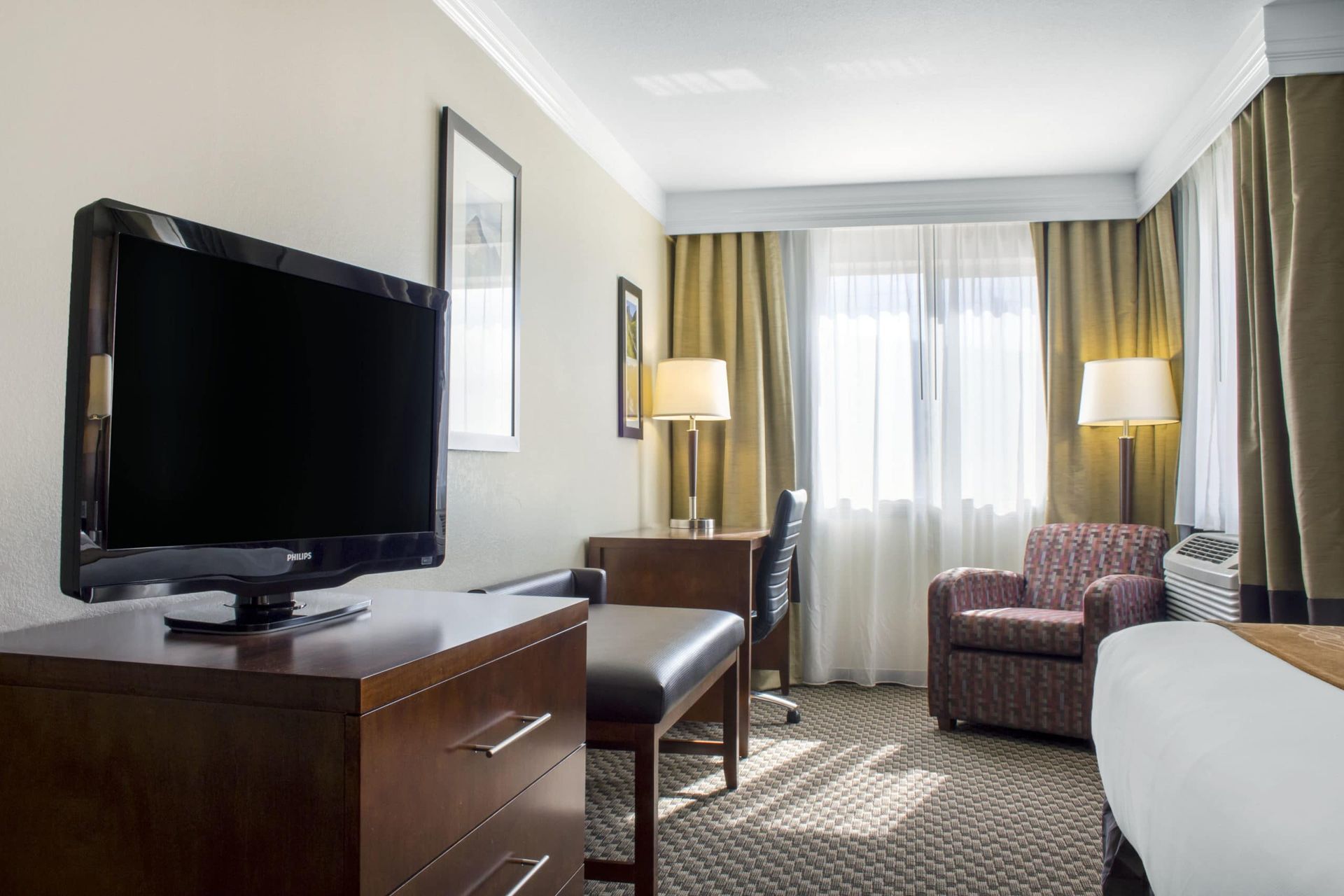 A hotel room with a large flat screen tv on the wall.