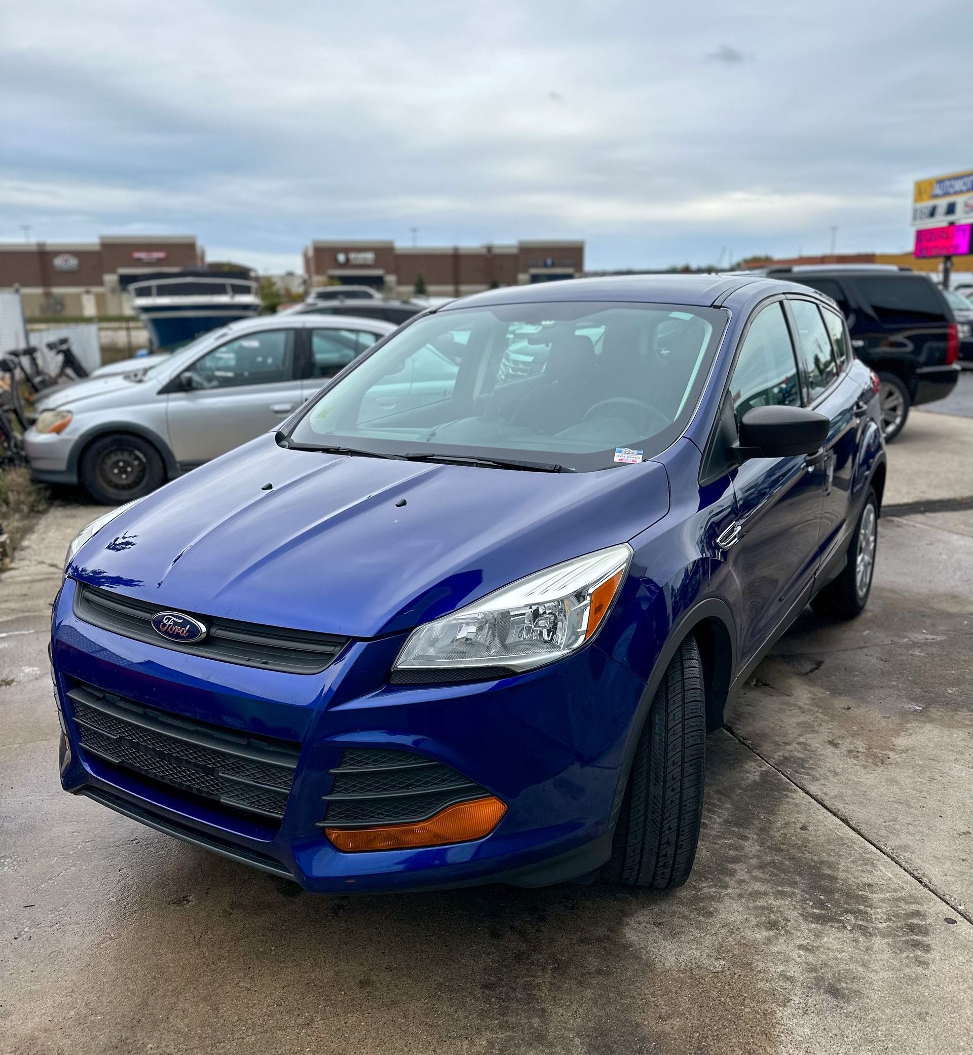 A blue ford escape is parked in a parking lot.