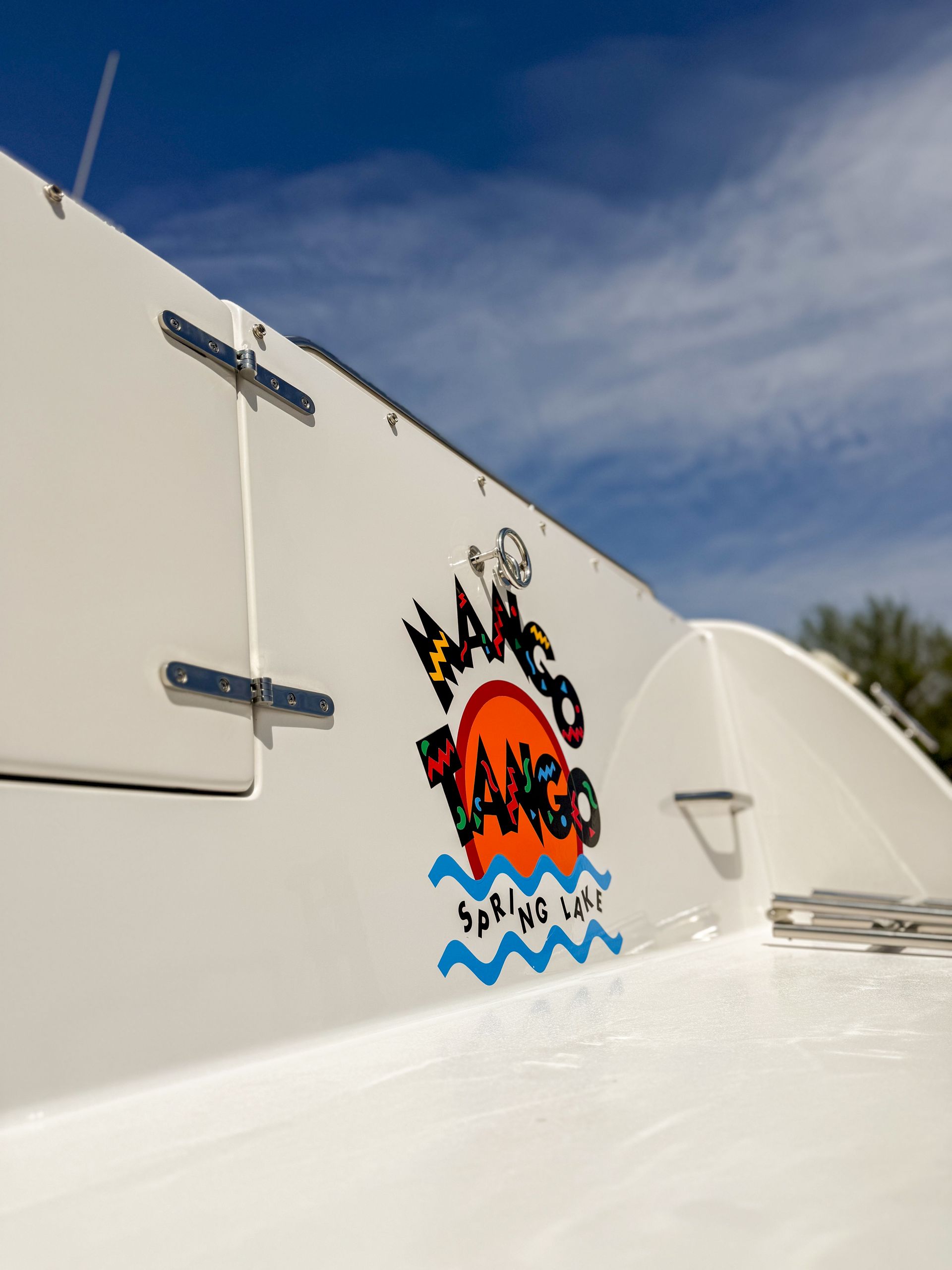 White boat deck with a colorful fish logo painted on the side under a blue sky