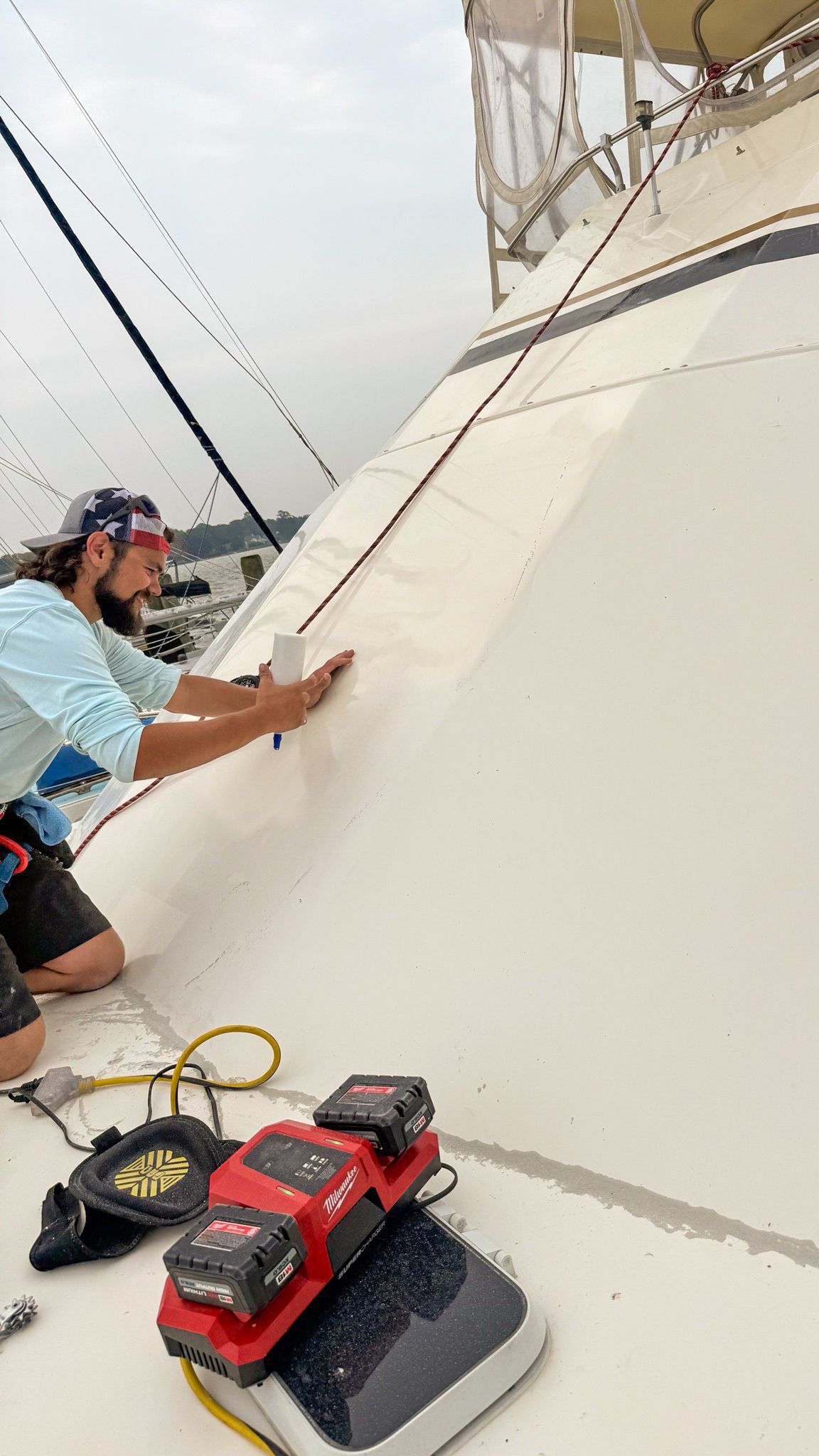 Worker on a rooftop using a tool on a white sloped surface, with equipment nearby.