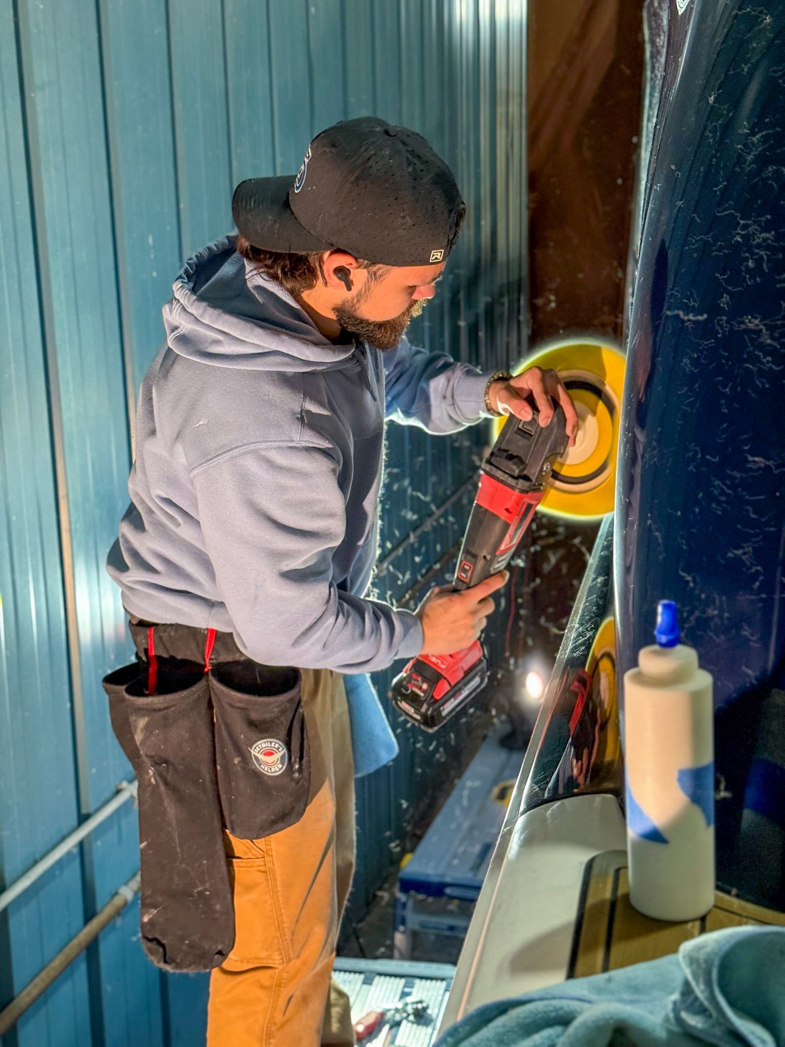 Person using a power tool to cut metal beside a blue wall, with sparks flying.