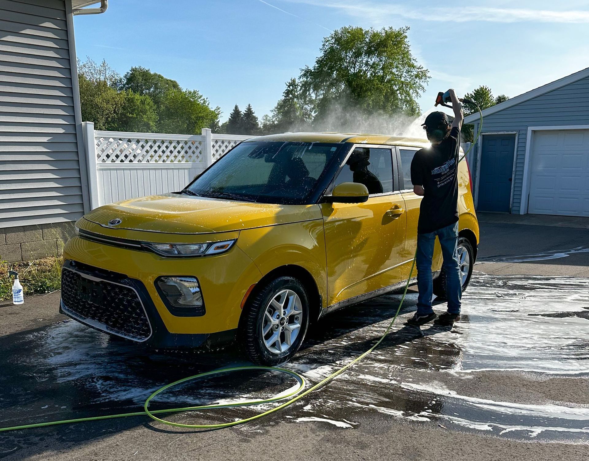 A car is being washed with a high pressure washer in a garage.