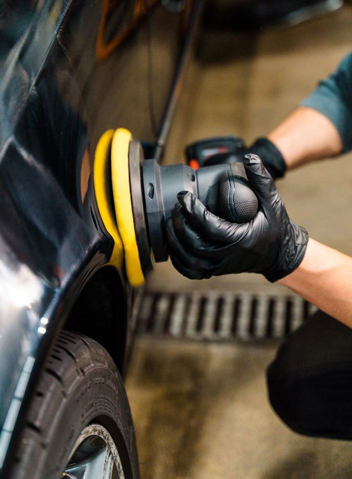 A person is polishing a car with a machine.