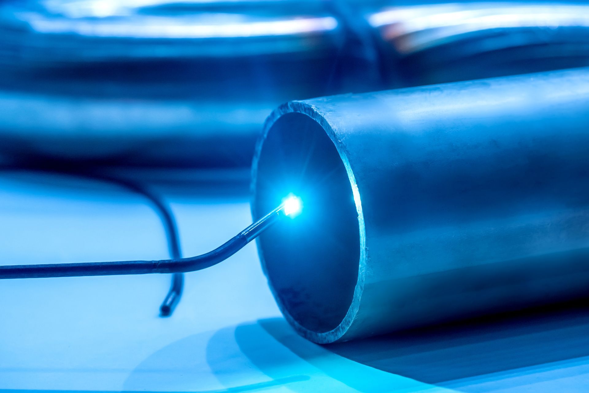 Blue glowing fiber optic cable end on a metallic tube background Blue glowing fiber optic cable end on a metallic tube background