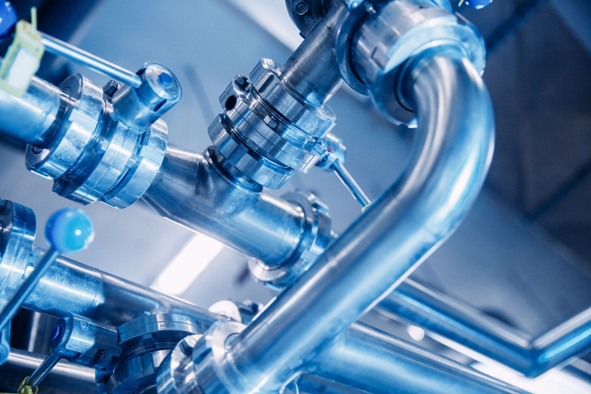 Shiny stainless steel industrial pipes with valves in a blue-lit facility Shiny stainless steel industrial pipes with valves in a blue-lit facility