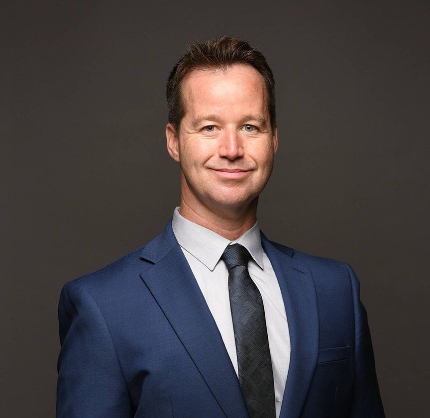Studio portrait of a man in a blue suit and tie against a dark gray background