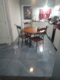 Small dining area with a round wooden table, four chairs, and a glossy gray tiled floor.