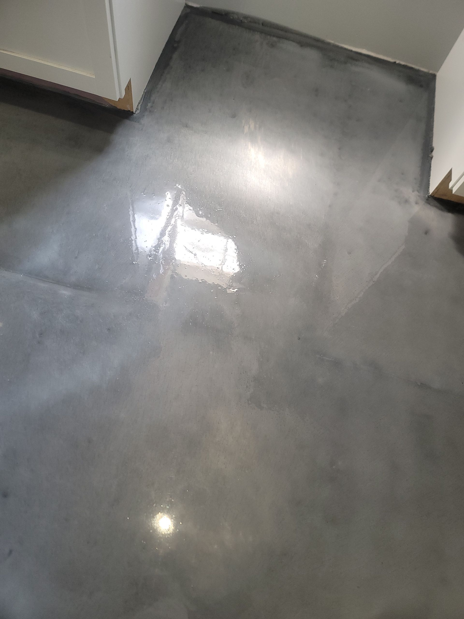 Shiny gray floor with bright reflections and cabinet edges in a hallway or room corner