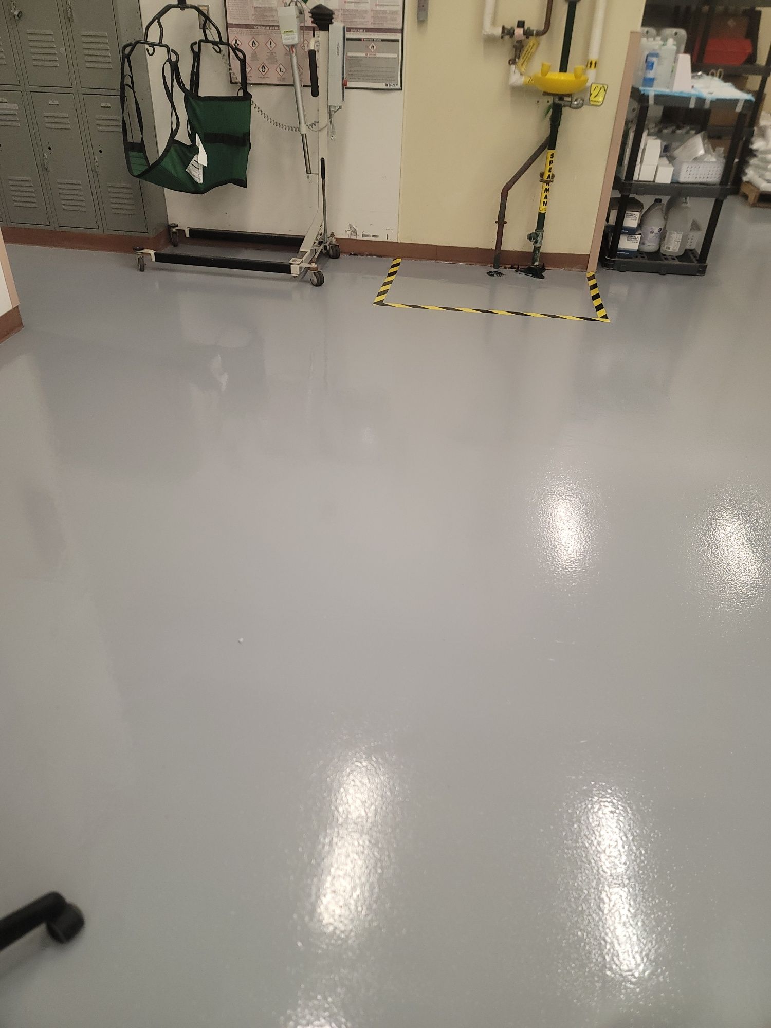 Empty industrial room with a glossy gray floor, wall equipment, and yellow caution markings.
