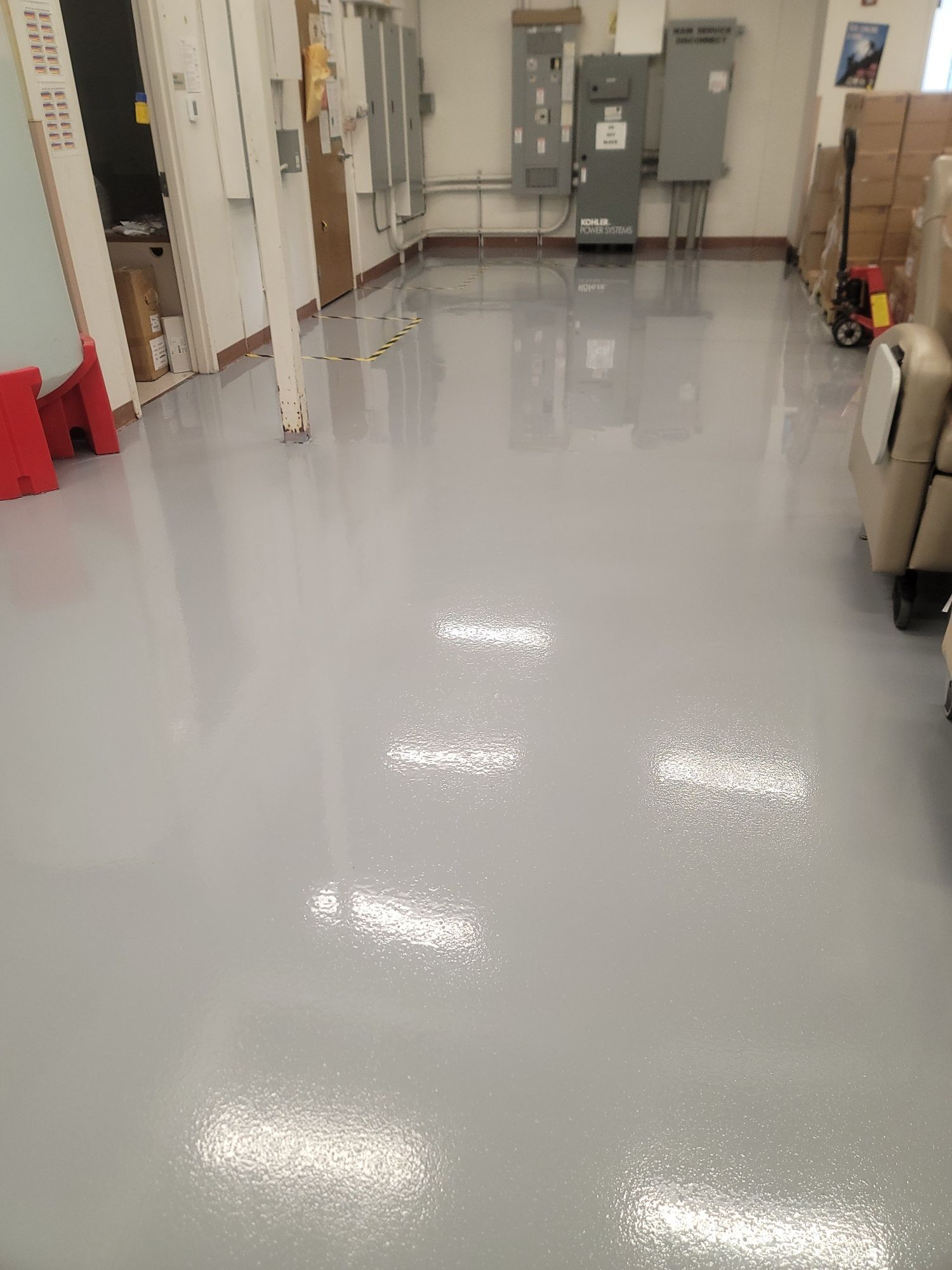 Glossy white industrial hallway with utility cabinets, doors, and cleaning equipment along the walls