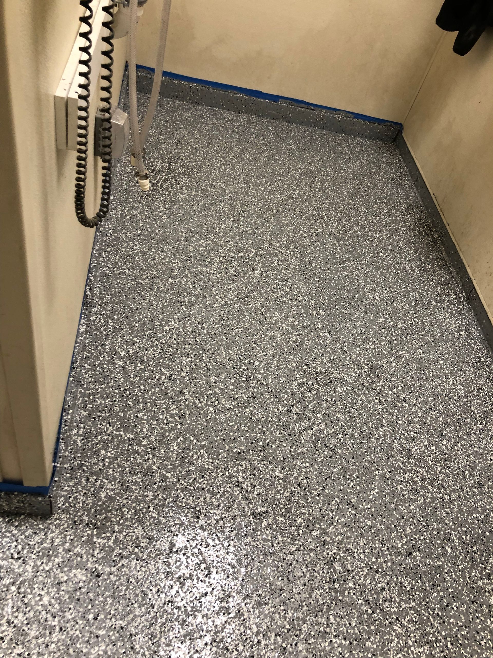 Narrow hallway with speckled gray floor and wall-mounted corded phone on the left.