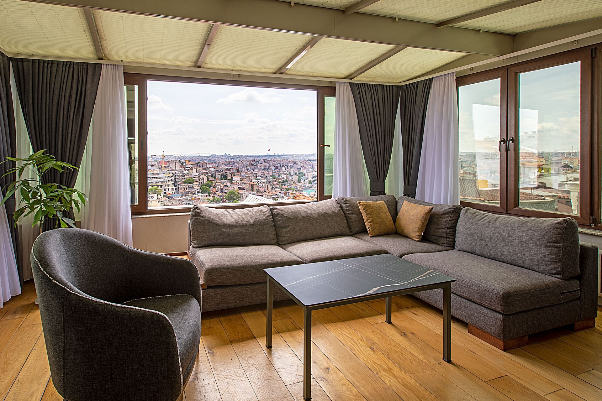 Cozy living room with gray sectional sofa, black coffee table, and city view through large windows