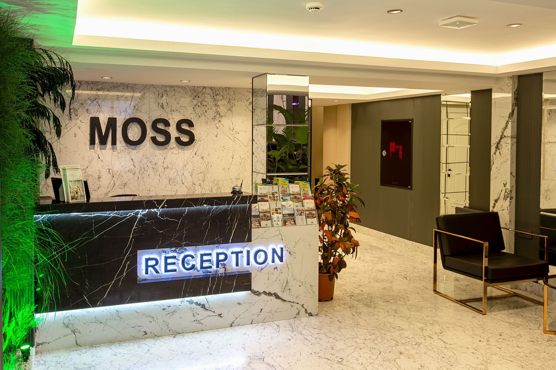 Lobby reception area with illuminated MOSS reception desk, marble walls, and seating