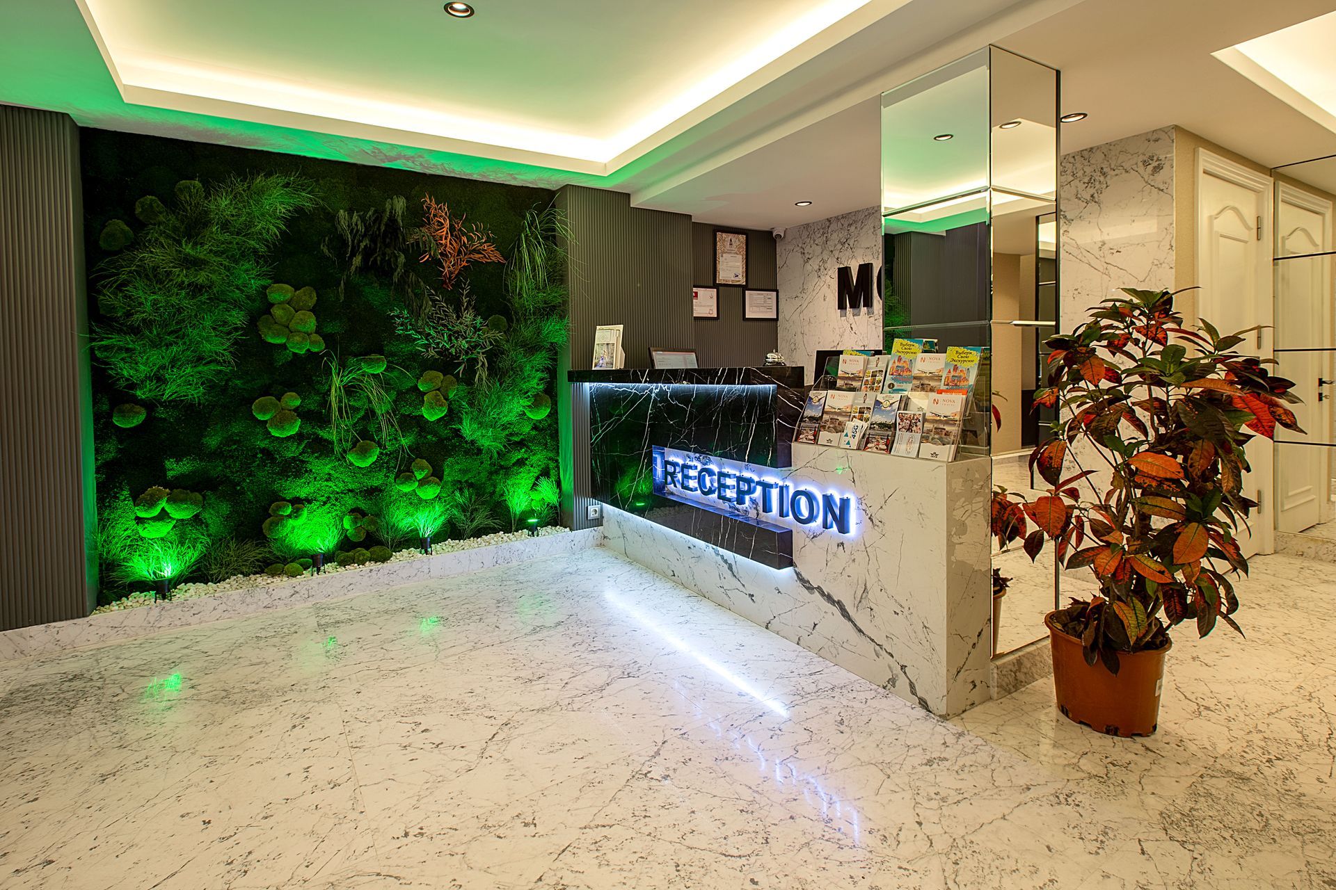 Modern reception lobby with marble desk, green plant wall, and potted plant decor
