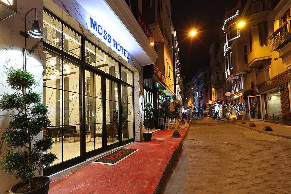 Nighttime street view of a modern storefront with bright lights and a red sidewalk on a quiet cobblestone road