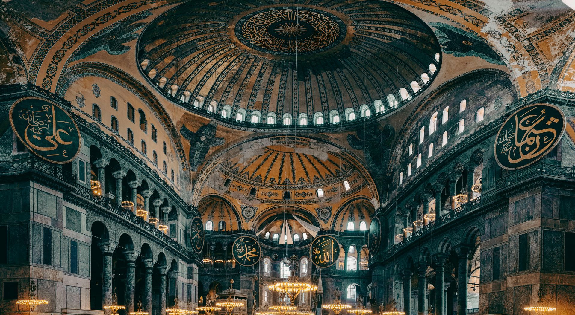 Hagia sofia mosque interior with a large domed ceiling, arches, and warm golden lighting