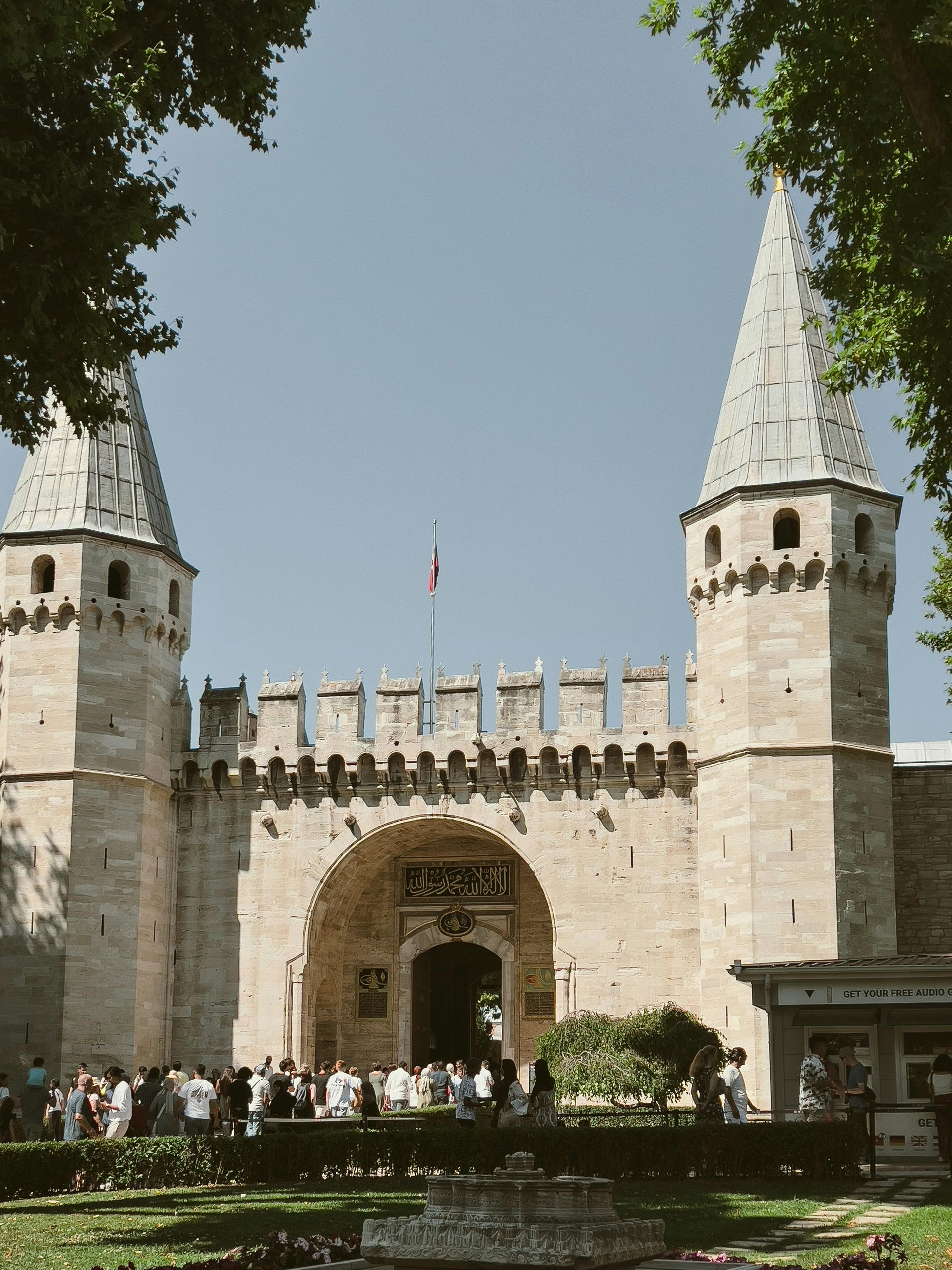İki kuleli taş kapı; önünde insanlar kuyruk oluşturuyor.