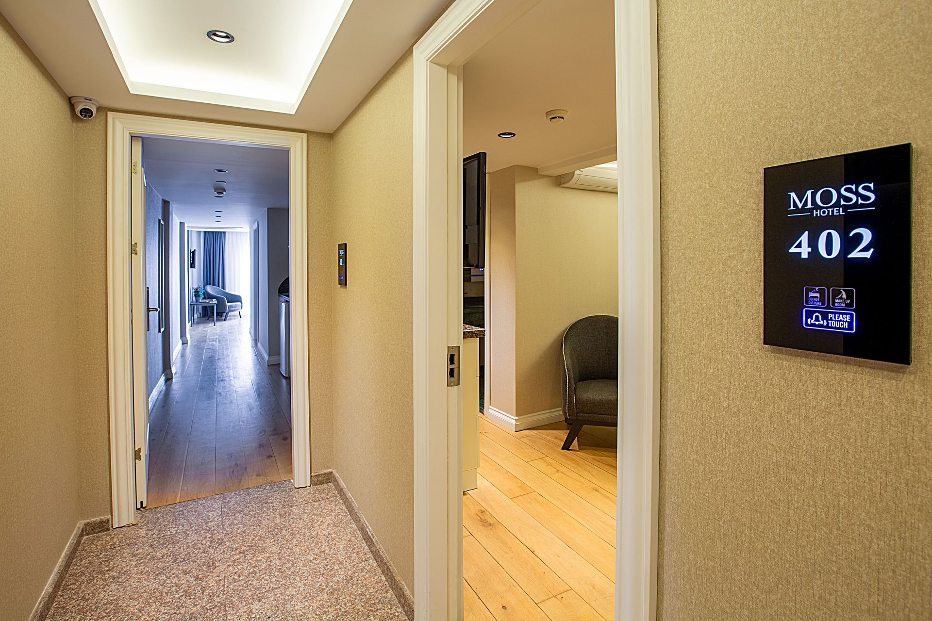 Apartment hallway with open doorway and wall sign reading “MOSS 402”