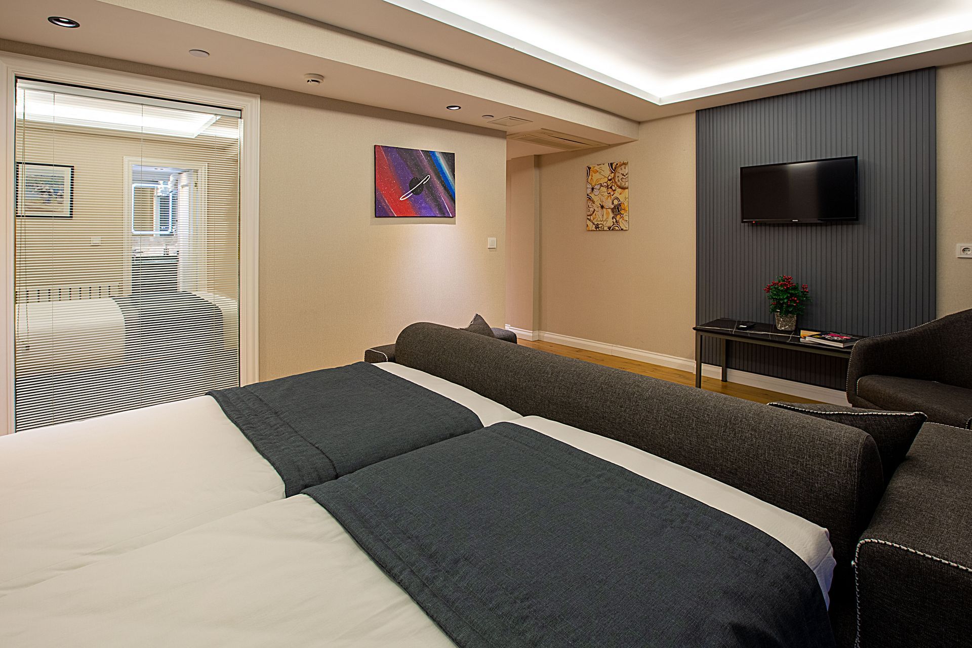 Modern hotel bedroom with a large bed, wall-mounted TV, and soft ambient lighting